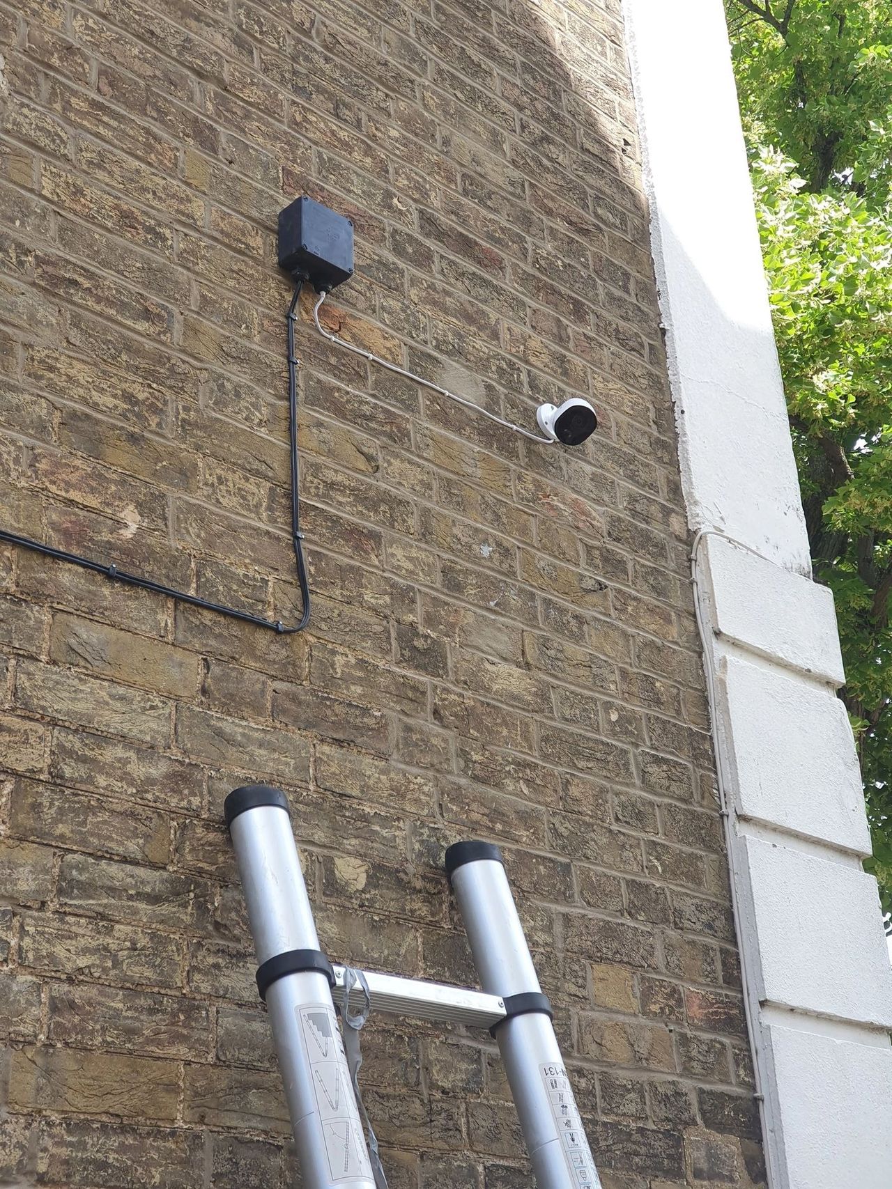 External CCTV camera and conduit installed on a brick wall