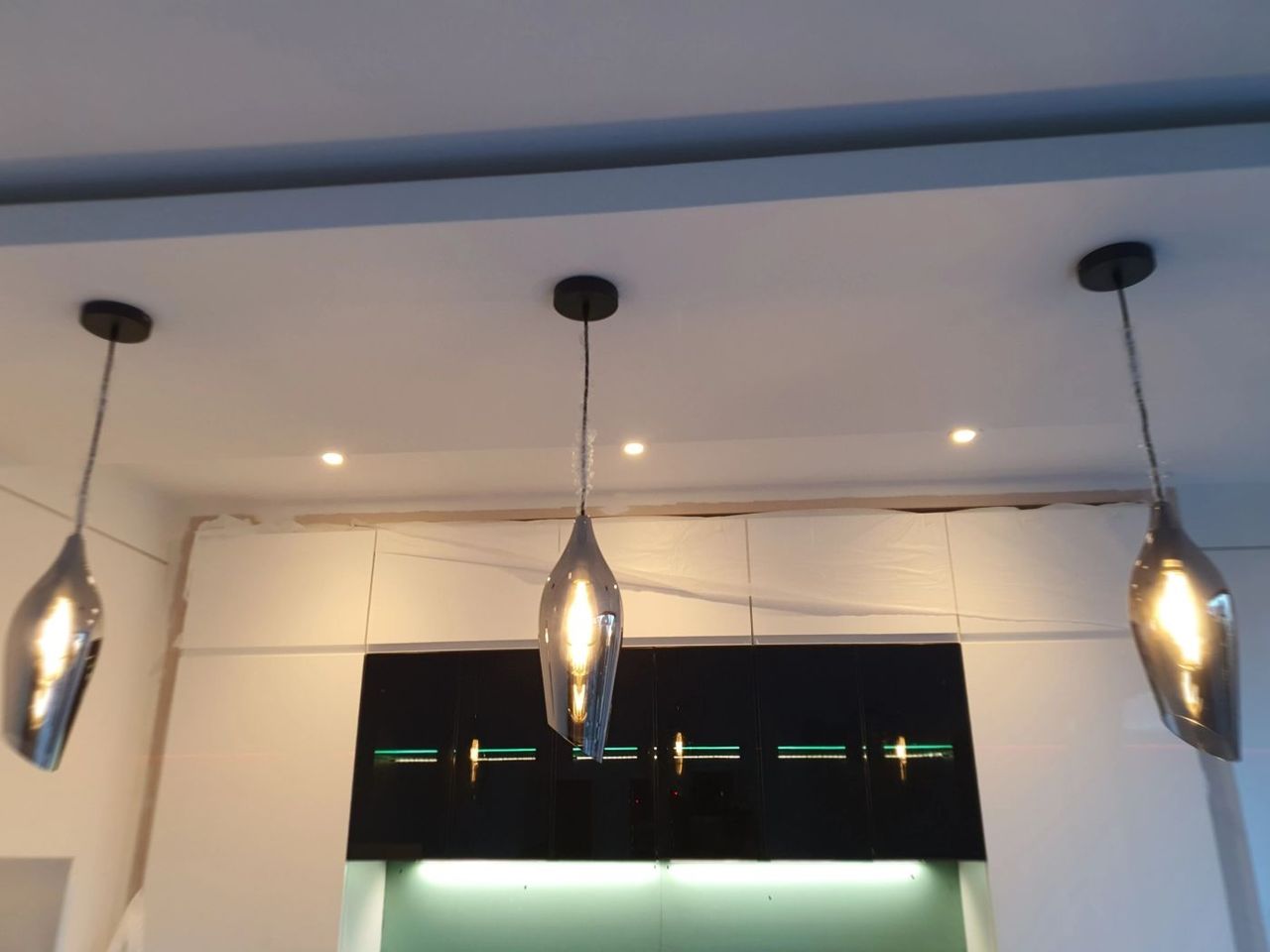 Three pendant lights and LED strip lighting over a kitchen island