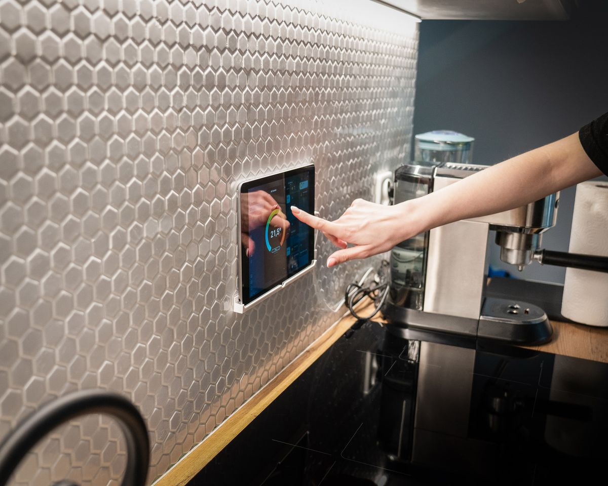 Wall-mounted smart home control panel being used in a kitchen